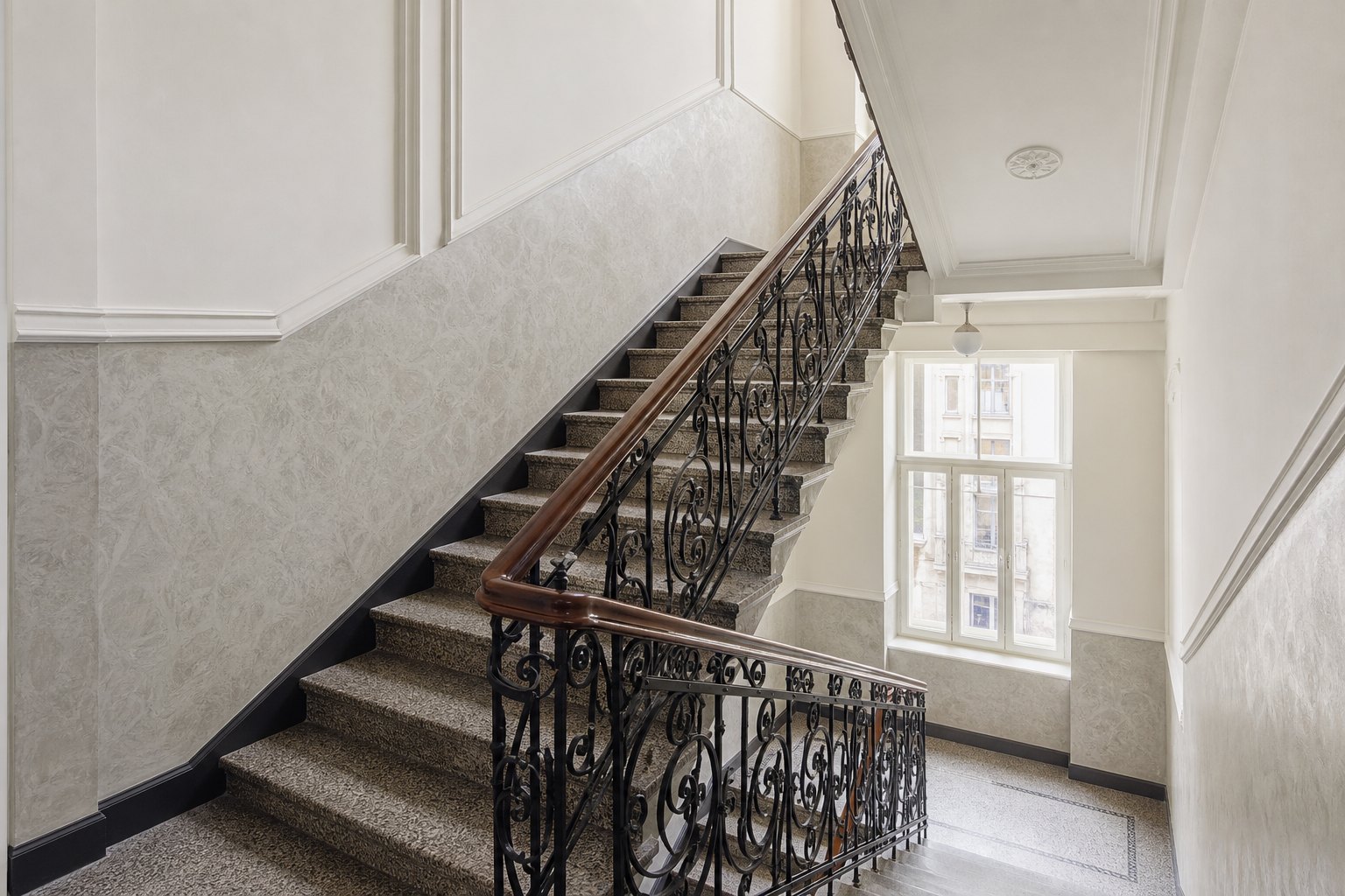 Odrestaurowana klatka schodowa zabytkowej kamienicy z kutą balustradą
